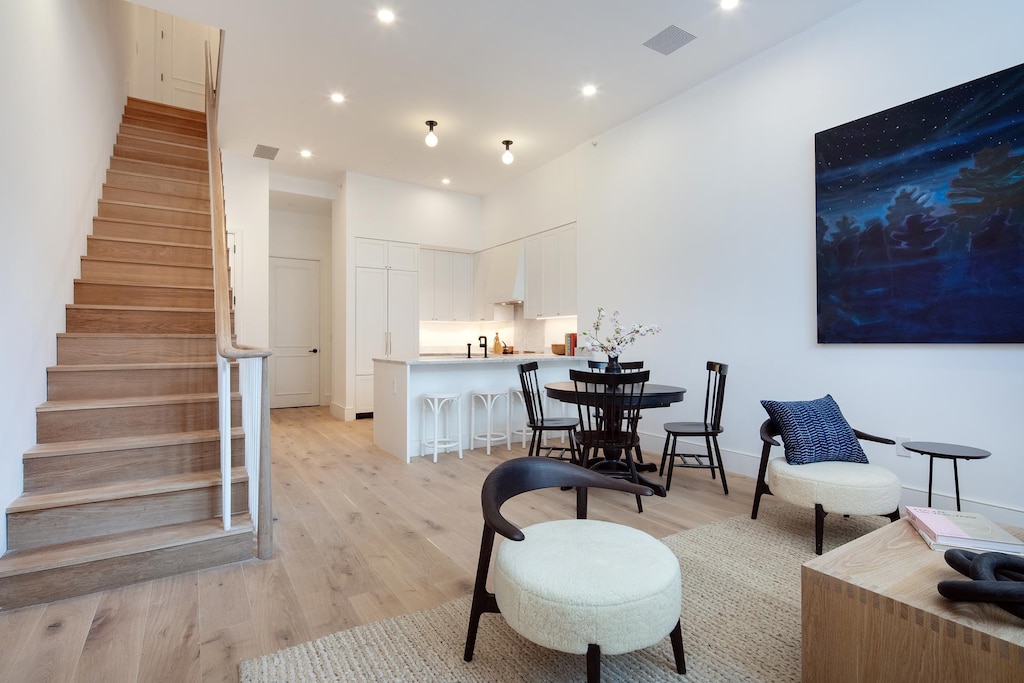 living area with light wood-type flooring, stairway, recessed lighting, and baseboards