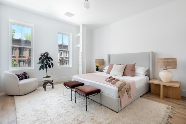 bedroom with baseboards, visible vents, and light wood finished floors