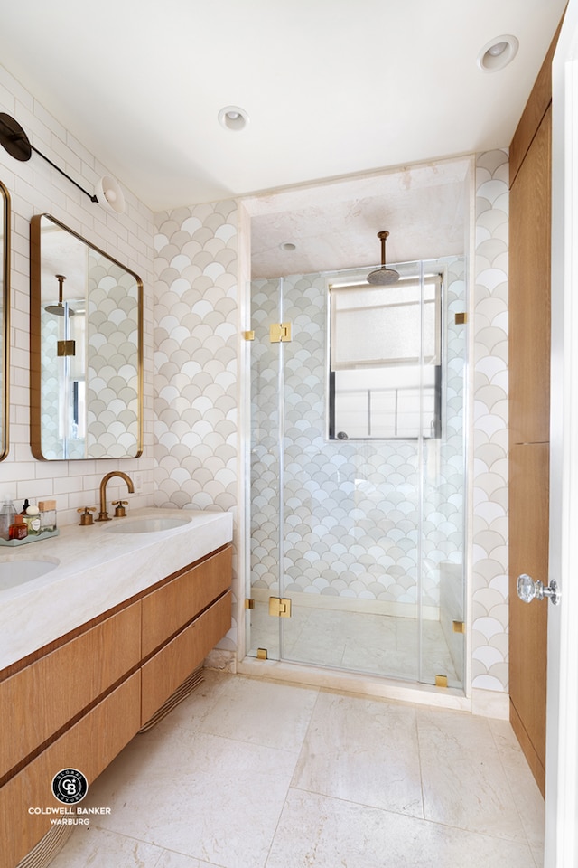 full bathroom with double vanity, a shower stall, tile walls, and a sink