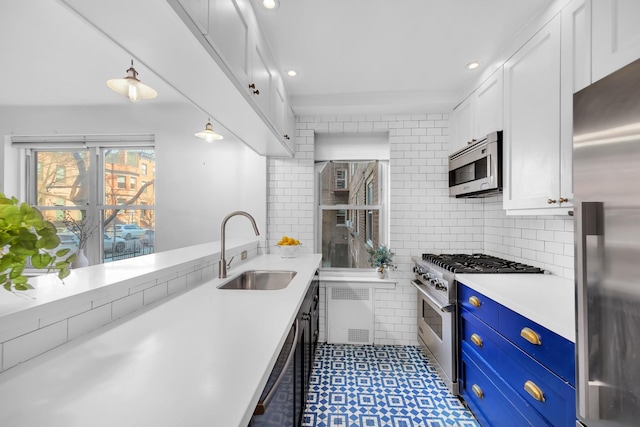 kitchen with white cabinets, stainless steel appliances, light countertops, blue cabinetry, and a sink