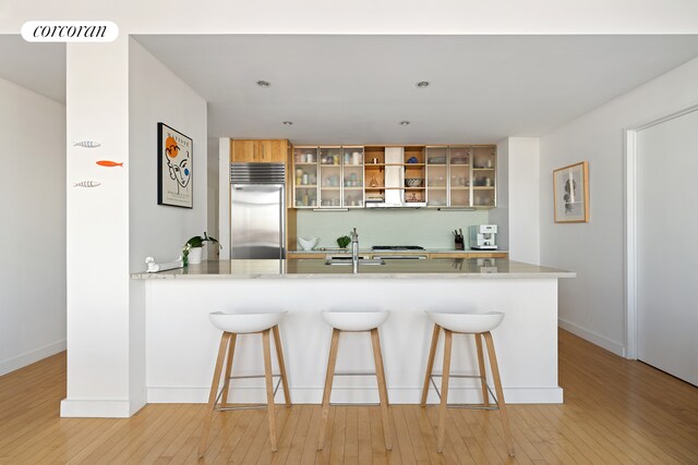 kitchen with tasteful backsplash, stainless steel built in refrigerator, light wood-type flooring, and visible vents