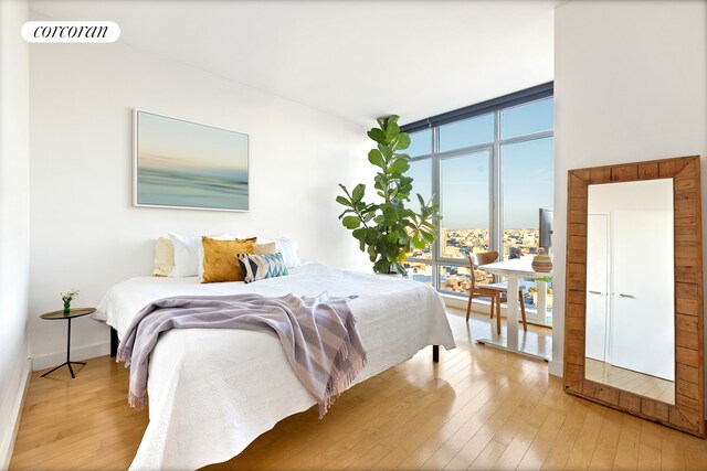 bedroom featuring wood-type flooring, expansive windows, and visible vents