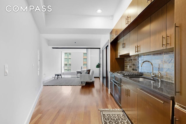 150 Myrtle Ave Unit 602, New York City, NY 11201 - kitchen with light wood finished floors, black oven, backsplash, baseboards, and a sink