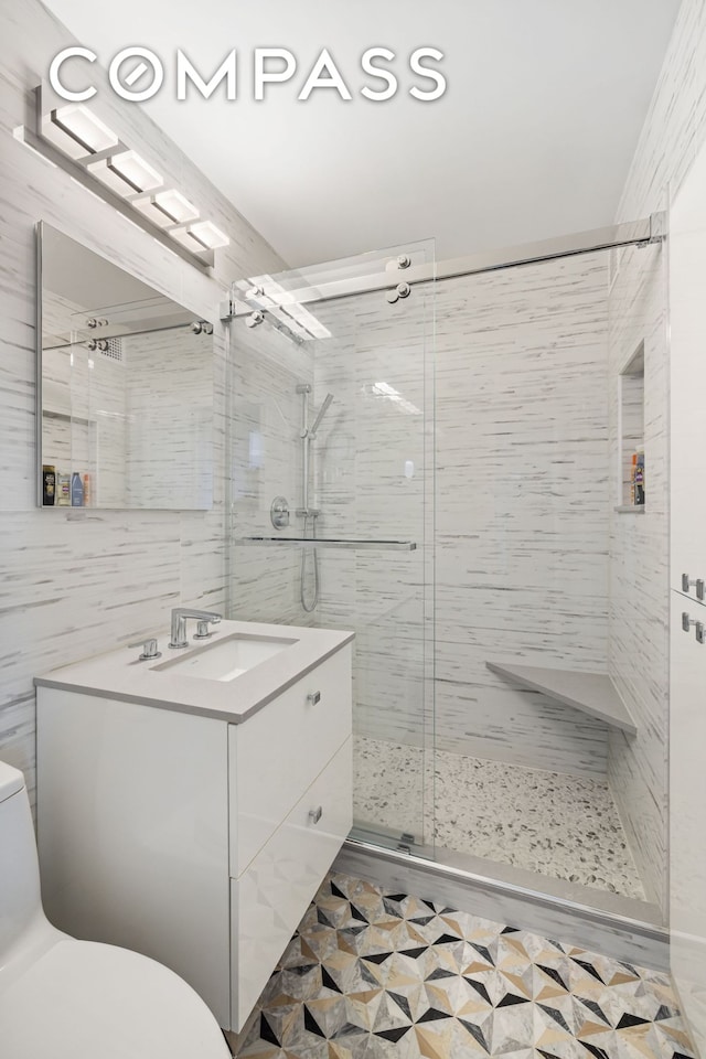 bathroom with tile walls, a shower stall, vanity, and toilet