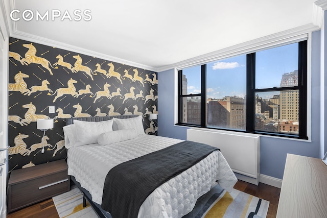 bedroom with an accent wall, wood finished floors, baseboards, a view of city, and crown molding