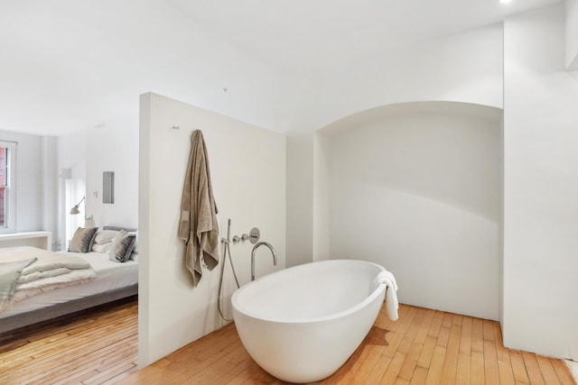 ensuite bathroom with hardwood / wood-style flooring, a freestanding bath, and ensuite bathroom