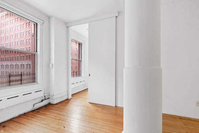 empty room with plenty of natural light, hardwood / wood-style flooring, and baseboard heating