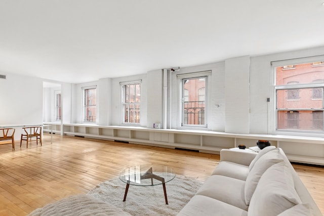 living room with a healthy amount of sunlight, visible vents, and hardwood / wood-style flooring