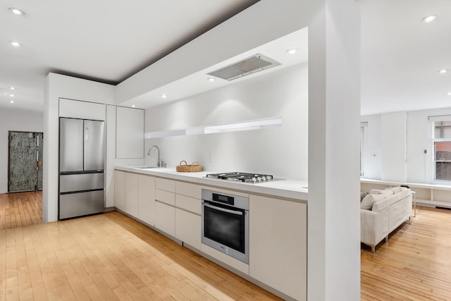 kitchen featuring stainless steel appliances, modern cabinets, a sink, and white cabinetry