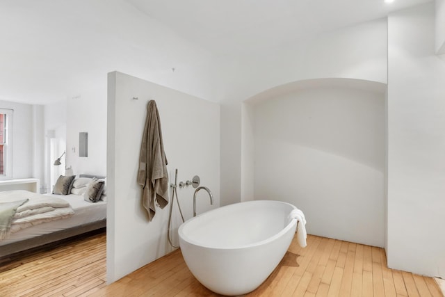 full bath with ensuite bathroom, hardwood / wood-style flooring, and a soaking tub