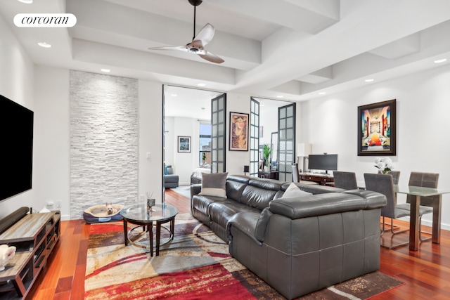 living area with a tray ceiling, visible vents, wood finished floors, and recessed lighting