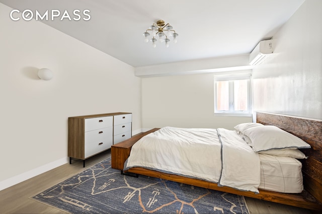 bedroom with a wall mounted air conditioner, wood finished floors, and baseboards