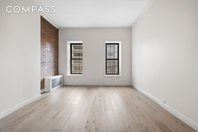 empty room with baseboards, wood finished floors, and crown molding