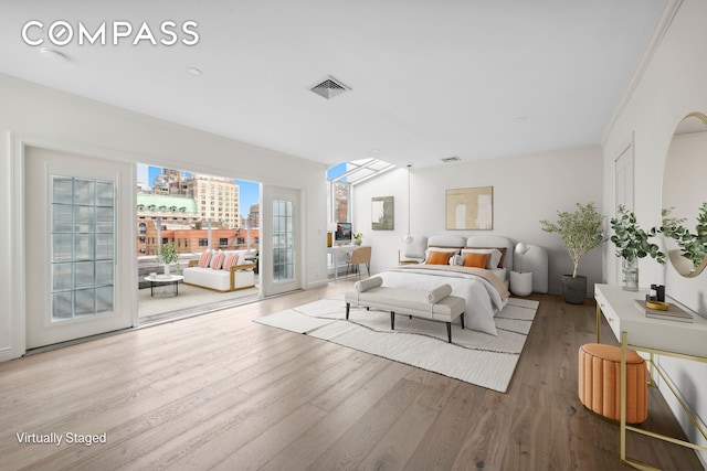 bedroom with visible vents, wood finished floors, access to outside, a view of city, and crown molding