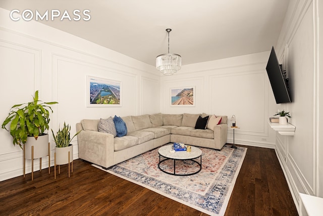 living room featuring a chandelier, dark wood-style flooring, and a decorative wall