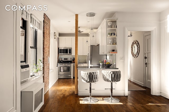 kitchen featuring a breakfast bar, white cabinetry, appliances with stainless steel finishes, open shelves, and dark wood finished floors