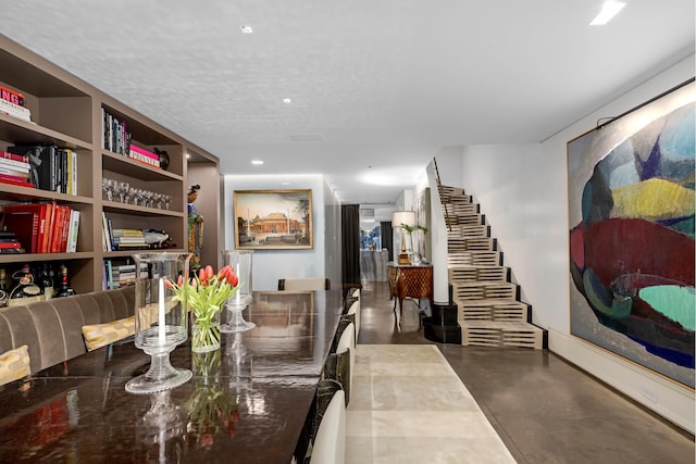 dining area with finished concrete floors, stairway, and a textured ceiling