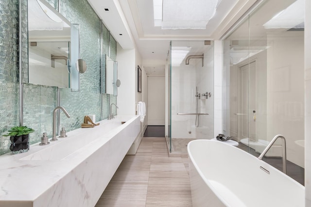 bathroom with a shower stall, a soaking tub, double vanity, and a sink