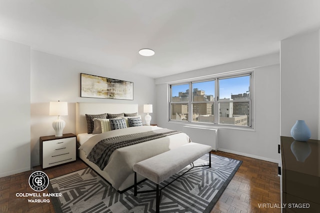 bedroom with a view of city, radiator heating unit, and baseboards