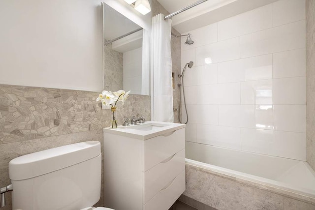 bathroom with vanity, tiled shower / bath combo, toilet, and tile walls