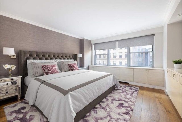 bedroom featuring light wood finished floors, ornamental molding, and wallpapered walls