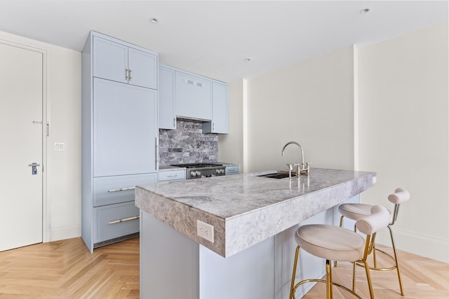 kitchen featuring a breakfast bar area, baseboards, a sink, range, and tasteful backsplash