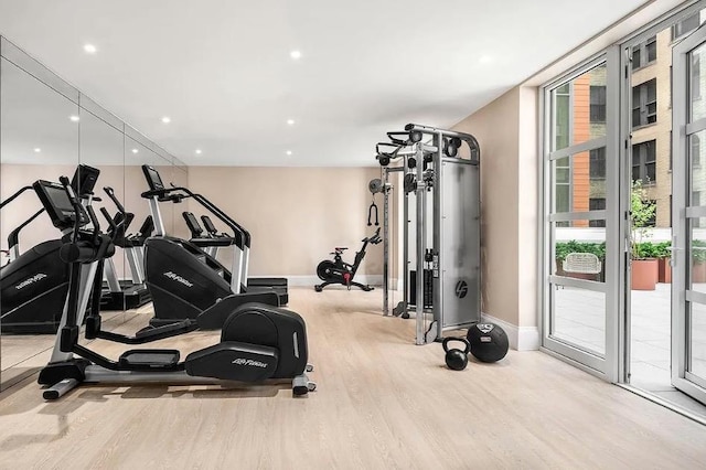 exercise room with recessed lighting, baseboards, a wall of windows, and wood finished floors