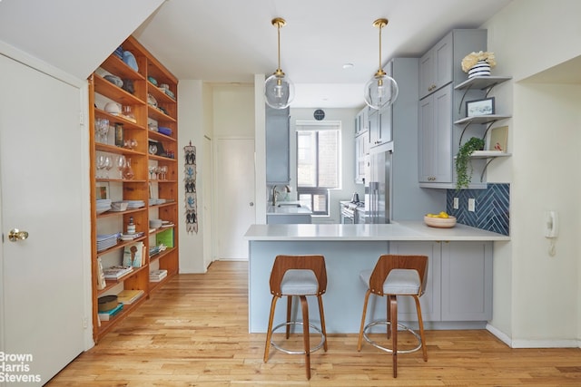 kitchen with open shelves, light wood-type flooring, light countertops, and gray cabinetry