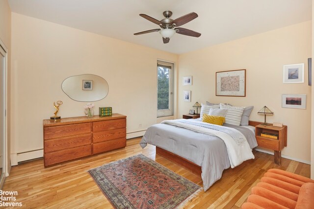 bedroom featuring a baseboard heating unit, light wood-type flooring, and ceiling fan