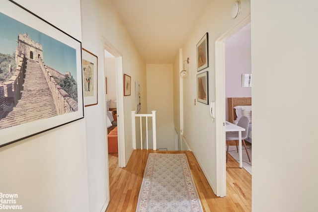 corridor with light wood-style flooring and an upstairs landing