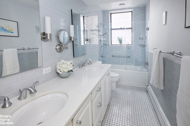 full bath with baseboard heating, a sink, tile walls, and toilet