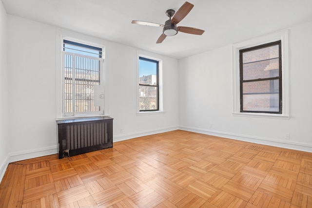 unfurnished room with radiator, ceiling fan, and baseboards