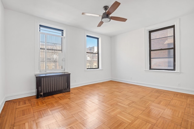 empty room with radiator, baseboards, and a ceiling fan
