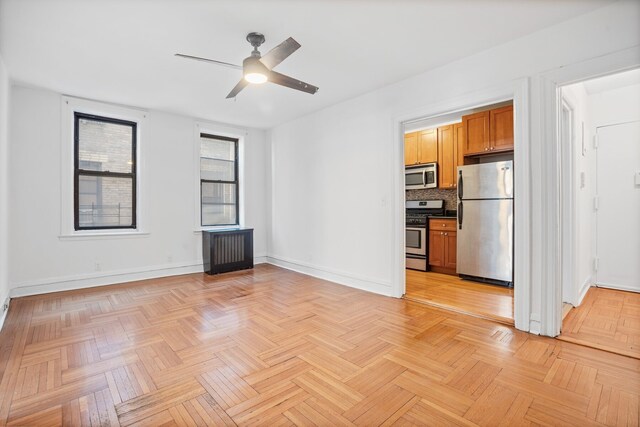 interior space featuring radiator heating unit, a ceiling fan, and baseboards