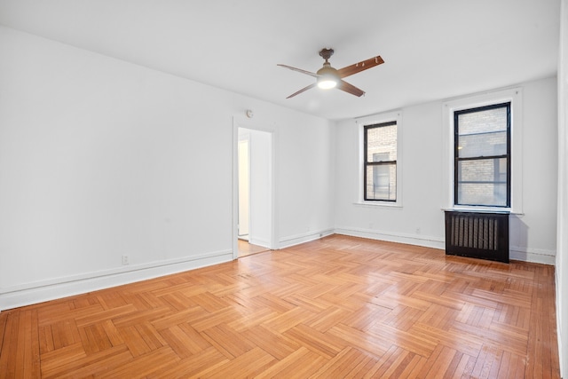 unfurnished room with radiator heating unit, a ceiling fan, and baseboards