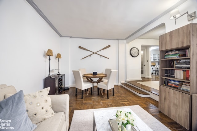 living area featuring arched walkways, crown molding, and baseboards