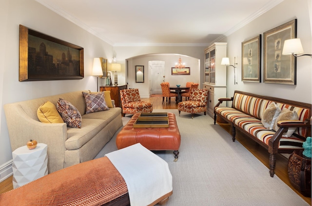 living area featuring crown molding, wood finished floors, arched walkways, and a chandelier