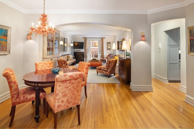 living room with arched walkways, crown molding, and wood finished floors