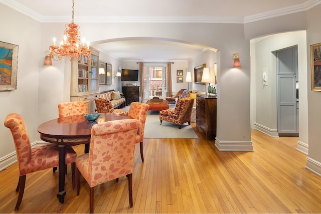 dining area featuring a chandelier, arched walkways, light wood-style floors, and ornamental molding