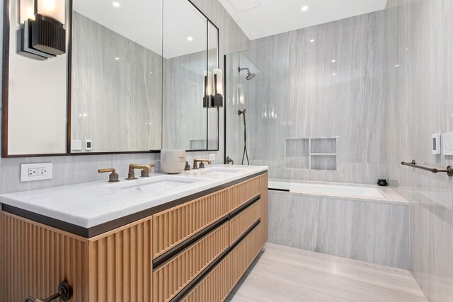 full bathroom with double vanity, a combined bath / shower with marble appearance, and a sink