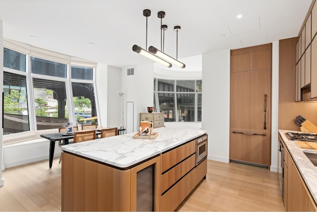 kitchen featuring light wood-type flooring, beverage cooler, modern cabinets, and visible vents