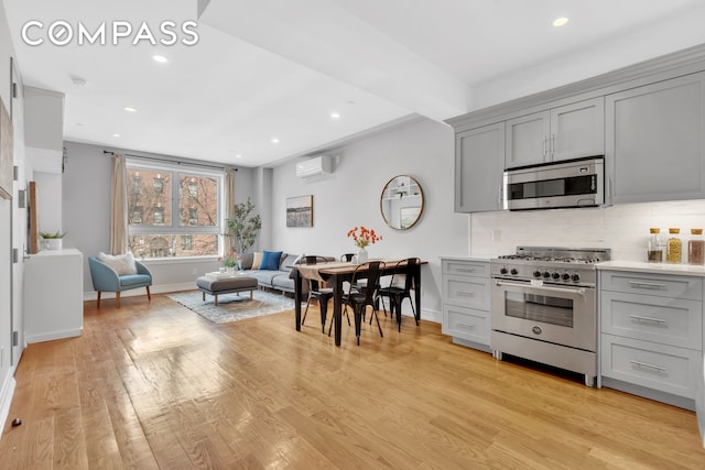 kitchen with tasteful backsplash, gray cabinets, stainless steel appliances, and light wood-type flooring