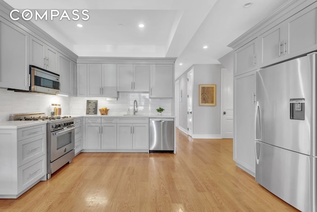 kitchen with light wood-style flooring, backsplash, recessed lighting, appliances with stainless steel finishes, and light countertops