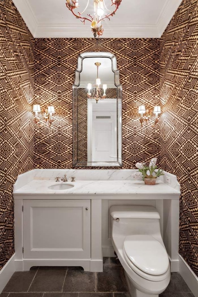 bathroom with a chandelier, crown molding, vanity, toilet, and baseboards