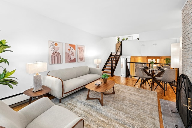 living room featuring stairway, a baseboard heating unit, and wood finished floors