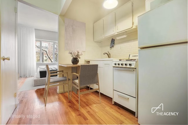 kitchen featuring white appliances, light wood-style flooring, decorative backsplash, light countertops, and white cabinets