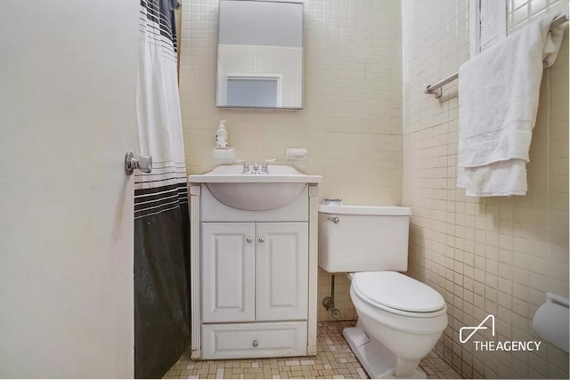 bathroom with vanity, tile patterned floors, toilet, and tile walls