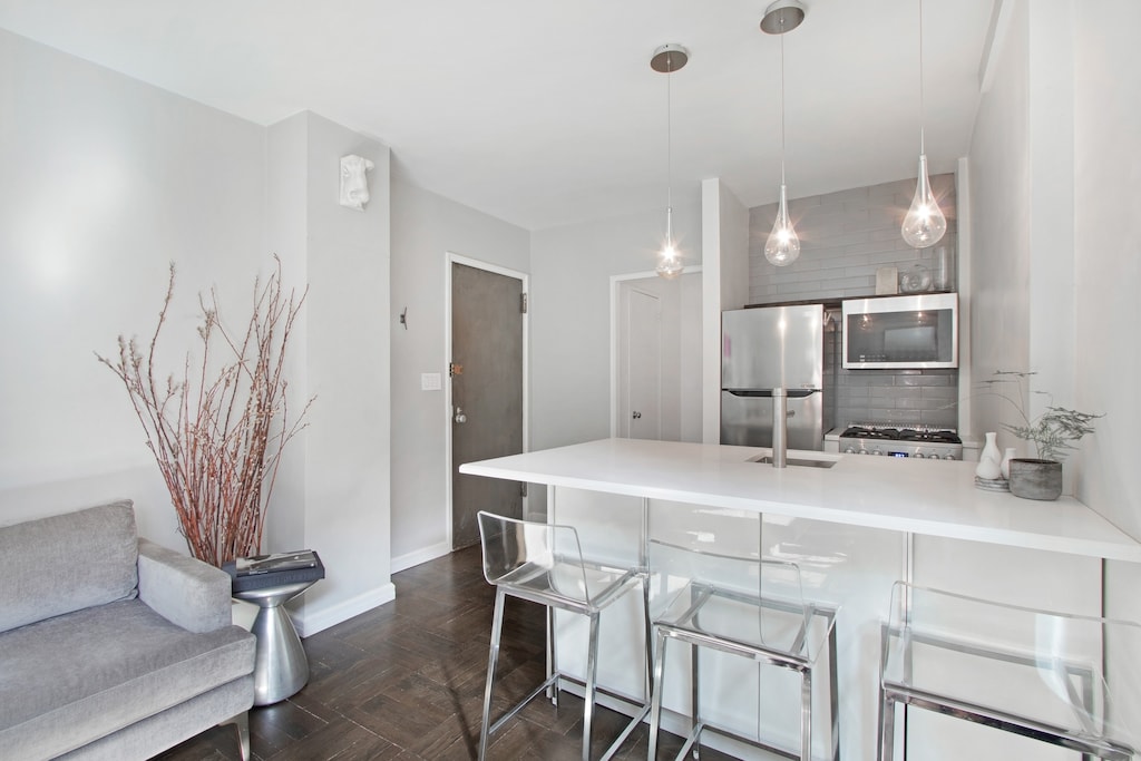 kitchen featuring baseboards, pendant lighting, a kitchen breakfast bar, a peninsula, and stainless steel appliances