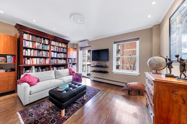 living area featuring a baseboard heating unit, wood finished floors, a wall unit AC, and a healthy amount of sunlight