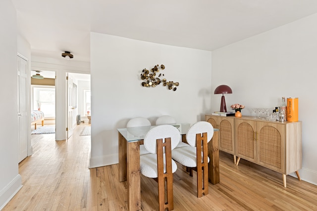 dining area with light wood-type flooring and baseboards